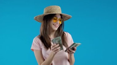 Amerikan doları sayan tatmin olmuş bir kadın. Asyalı genç bir kız ya da öğrenci para sayıyor. Mavi duvarda dolar banknotları. Başarının, kazancın, maaşın, faydanın, yatırımların sembolü. Yüksek kalite 4k