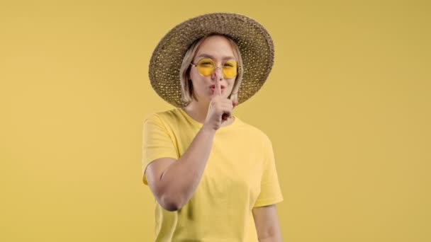 漂亮的女士有着沉默 八卦的姿态 微笑的女人把手指放在嘴唇上 黄色的工作室背景 是的高质量的4K镜头 — 图库视频影像