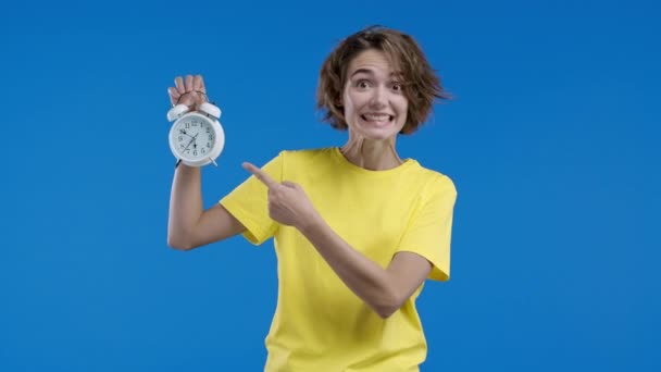 青い背景に目覚まし時計を持つ幸せな女性 正しい一日のルーチンは 瞬間に住んで 若者のすべての分に感謝します 高品質4K映像 — ストック動画