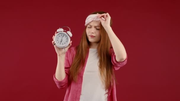 目覚まし時計の眠い女が手に持って目を覚ました 赤の背景 早朝6時頃 怠惰な女性は十分な睡眠 時間を渡すことの概念を取得していない 高品質4K映像 — ストック動画