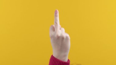 Rude woman on yellow background showing middle finger - gesture of fuck. Expression negative, aggression, provocation. High quality 4k footage