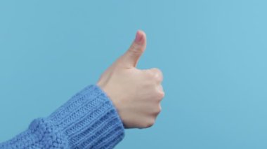 Tanımlanamayan bir kadın el işaretini baş parmak hareketine çeviriyor. Doğru mükemmel seçim, harika bir anlaşma, mavi arka plan. Pozitif, onay, güven konsepti. Yüksek kalite 4k görüntü
