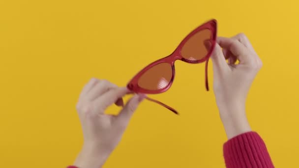 Damskie Dłonie Trzymające Czerwone Okulary Przeciwsłoneczne Stylu Retro Żółtym Tle — Wideo stockowe