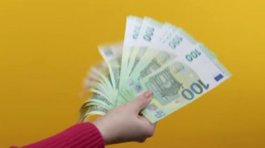 Nakit parası olan kadın - Sarı arka planda 100 avro nakit para birimi. Piyango, piyango ödülü, maaş, karlı yatırım. Yüksek kalite 4k görüntü