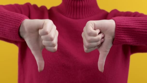 嫌いの印を持つ女性 親指を示すことに不満を表明ジェスチャー 黄色の背景 間違った悪い選択 高品質4K映像 — ストック動画