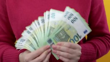 Nakit parası olan kadın - Kırmızı arka planda 100 avro nakit para birimi. Piyango, piyango ödülü, maaş, karlı yatırım. Yüksek kalite 4k görüntü