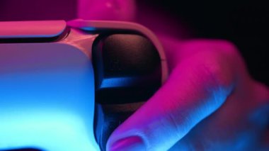 Oyuncuların elleri konsol TV 'de oyun oynuyor. Kumandalı, neon renkli ışık. Kadın düğmelere basıyor, kumanda kullanıyor, en yeni kablosuz oyun sahası. Hobi, e-spor, makro görüş. 4k görüntü