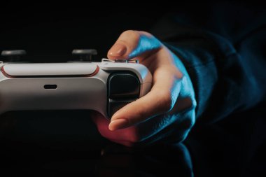 Oyuncuların elleri konsol TV 'de oyun oynuyor. Kumandalı, neon renkli ışık. Kadın düğmelere basıyor, kumanda kullanıyor, en yeni kablosuz oyun sahası. Hobi, e-spor, makro görüş. Kaliteli fotoğraf.