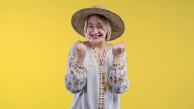 Sarışın Ukraynalı kadın zafer gösteriyor evet evet zafer işareti, sonuç elde edildi, hedefler. Mutlu, mutlu, şaşırmış, sarı arka plandaki mutlu bayan. Zafer konsepti. Yüksek kalite 4k görüntü