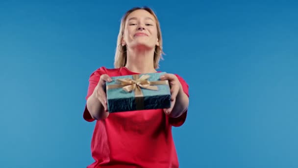 Γυναίκα Δίνει Κουτί Δώρου Χέρια Στην Κάμερα Μπλε Φόντο Κορίτσι — Αρχείο Βίντεο