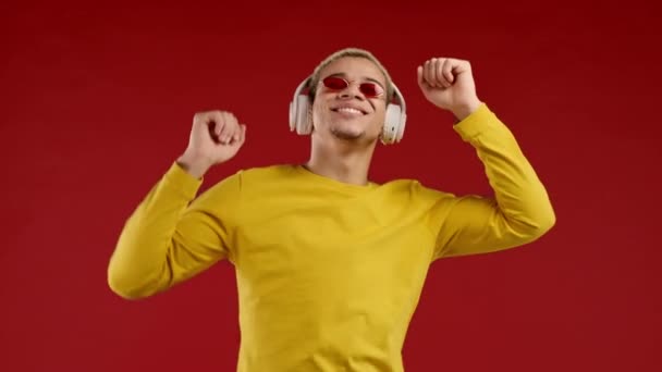 Позитивный Американец Слушает Музыку Наслаждается Танцем Наушниками Красном Фоне Студии — стоковое видео