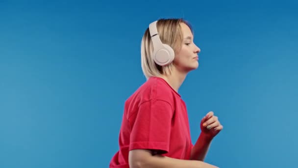 Positiv Blond Kvinna Lyssnar Musik Njuter Dans Med Hörlurar Blå — Stockvideo