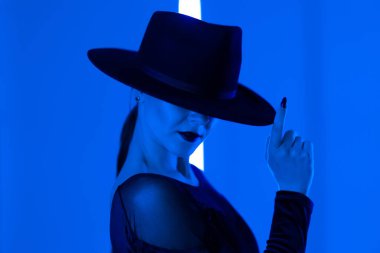 Tanımlanamayan seksi kadın, koyu renkli mavi ışıkla koyu renkli neon stüdyo arka planında parmak uçlarında koşuyor. Ölümcül kadın, şık bir balerin kıyafeti. Yüksek kalite fotoğraf