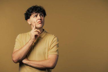 Düşünen adam sarı arka planda etrafa bakıyor. Dalgın yüz ifadeleri için endişelenmiş. Yakışıklı erkek model. Yüksek kalite fotoğraf