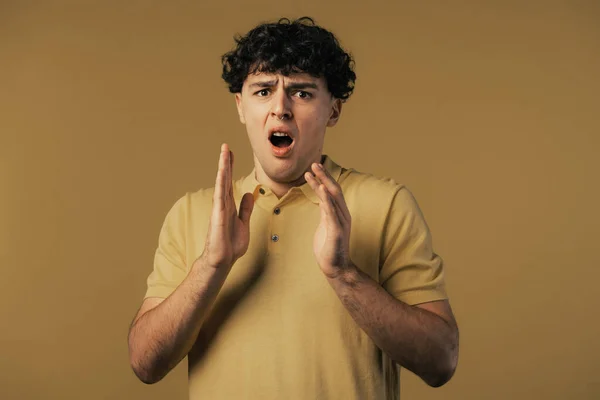 Frightened shocked man afraid of something and looks into camera with big eyes full of horror on yellow background. Phobia, trouble, panic concept. High quality photo