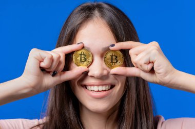 Bitcoin 'i olan kadın, kripto para birimi. Gözlerde altın para, mavi arka plan. Dijital değişim, BTC 'nin popülerliği, geleceğin parası, elektronik endüstrisi, madencilik konsepti. Yüksek kalite fotoğraf