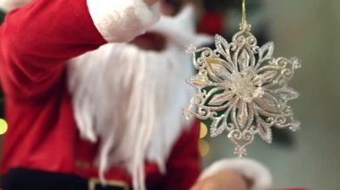 Kar taneli Noel ağacı oyuncağının yakın çekimi. Şenlik arka planı. Noel Baba kostümü ve yapay sakallı komik çocuk. Mutlu bir çocukluk geçirin çocuklar, sevgili oğlum. Yüksek kalite 4k görüntü