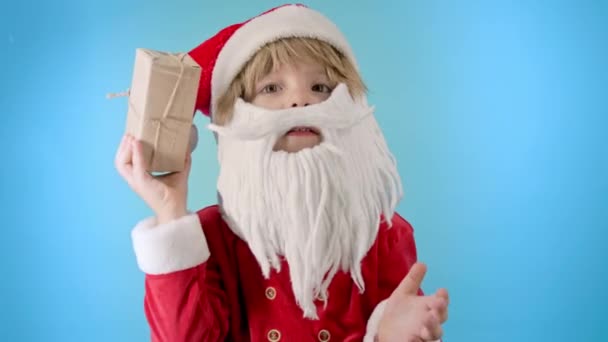 兴奋的圣诞老人 身穿圣诞老人服装 留着胡子 手里拿着礼品盒和弓 孩子不知道里面是什么 快乐的孩子与礼物 蓝色的圣诞背景高质量的4K镜头 — 图库视频影像