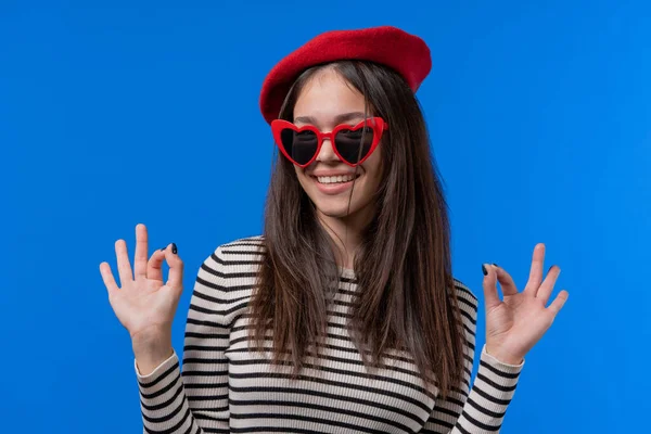 Güzel bir kadın el işareti yaptırır, tamam mı? Mutlu genç kız, doğru seçim, harika bir anlaşma, mavi özgeçmiş. Pozitif kadın model kameraya gülümser, onay, güven konsepti. Yüksek kalite fotoğraf