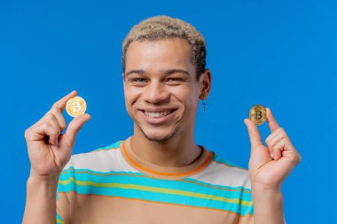 Man with bitcoins, crypto currency. Golden coin on blue background. Digital exchange, popularity of BTC, symbol of future money, electronics industry, mining concept. High quality photo
