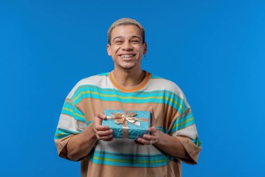 Happy birthday man with gift box on blue background. African american surprised guy, joy, he is happy with present. High quality photo