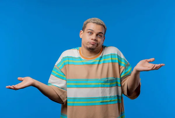 Confused man, shoulders up - can\'t help, makes gesture of I dont know. Difficult question, guilty reaction, puzzled guy on blue background. High quality photo