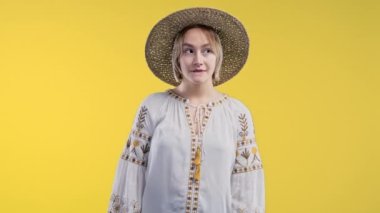 Smiling ukrainian woman holding finger on lips, yellow studio background. Pretty lady with gesture of shhh, secret, silence, conspiracy, gossip concept. High quality 4k footage