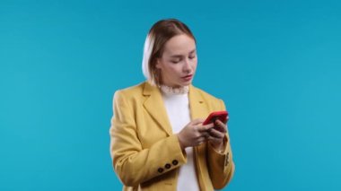 Pretty woman texting with message on smartphone. Lady on blue background. Tech, success, happiness, social networks concept. High quality 4k footage