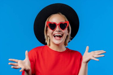 Amazed woman, she expresses WOW. Impressed teenager trying to get attention. Concept of sales, profitable offer. Excited hipster girl on blue background. High quality photo