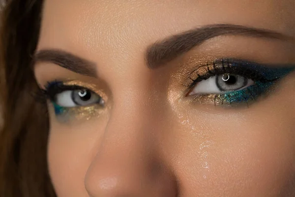 Ukrainian woman close-up, eyes crying, tears running down face. Pain, war, resentment, frustration. Yellow and blue make-up as symbol of Ukraine, flag.