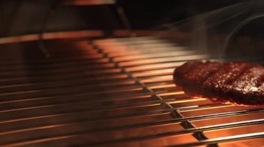 Izgara ızgarada biftek kızartma işlemi yapılıyor. Biftek ya da domuz köftesi. Hamburger için çiğ pirzola. Dolly 'nin yakın çekim görüntüsü.