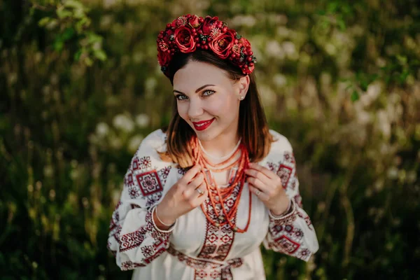 Attractive ukrainian woman in traditional embroidery vyshyvanka dress, ancient coral beads and red flowers wreath. Ukraine, freedom, culture, national costume, victory in war