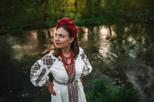 Attractive ukrainian woman in traditional embroidery vyshyvanka dress, ancient coral beads and red flowers wreath. Ukraine, freedom, culture, national costume, victory in war