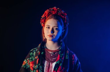 Charming ginger woman in traditional ukrainian handkerchief, necklace and embroidered blouse at black background. Ukraine, style, folk, ethnic culture. High quality photo