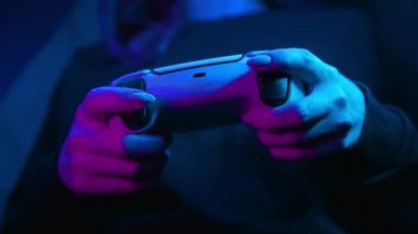 Odesa, Ukrayna - Nisan 2023. Oyuncuların elleri PlayStation 5 PS5 konsol televizyonunda neon ışığı altında online video oyunu oynuyor. Kadın düğmelere basıyor, joypad çift duyu kumandası kullanıyor