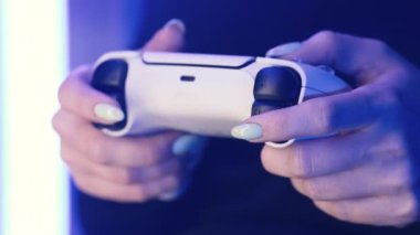 Odesa, Ukrayna - Nisan 2023. Oyuncuların elleri PlayStation 5 PS5 konsol televizyonunda neon ışığı altında online video oyunu oynuyor. Kadın düğmelere basıyor, joypad çift duyu kumandası kullanıyor