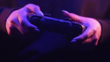 Odesa, Ukrayna - Nisan 2023. Oyuncuların elleri PlayStation 5 PS5 konsol televizyonunda neon ışığı altında online video oyunu oynuyor. Kadın düğmelere basıyor, joypad çift duyu kumandası kullanıyor
