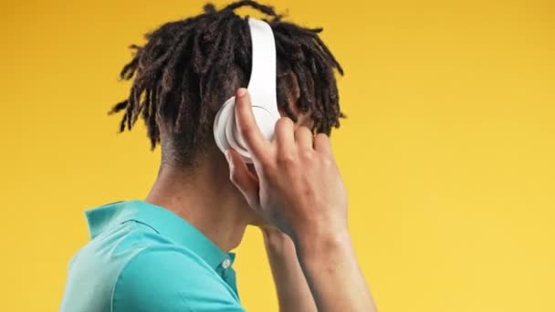 积极的非洲裔美国人听着音乐 喜欢用黄色录音室背景的耳机跳舞 无线电 无线现代音响技术 在线播放器 高质量的照片 — 图库视频影像