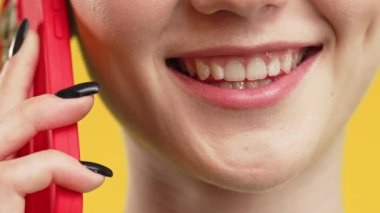 Bir kadının ağzı. Hanımefendi arkadaşınızla telefonla, uzaktan iletişim kurarak, hoş bir şaka yaparak, sarı arka planda şaşırtıcı bir şekilde hoş sohbetler edin. Telefon görüşmesi.