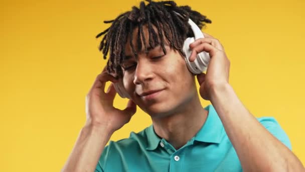 积极的非洲裔美国人听着音乐 喜欢用黄色录音室背景的耳机跳舞 无线电 无线现代音响技术 在线播放器 高质量4K — 图库视频影像