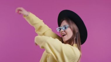 Eğlenceli güzel bir kadın, en sevdiği müzik, gülümseyen, pembe stüdyo arka planında dans eden. Müzik, dans konsepti, ağır çekim