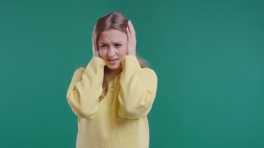 Sarı arka planı görmezden gelen, kulakları kapalı, sinirli kızıl bir kadın. Gençlerin rahatsız edici sesleri, bağırışları ya da gürültüyü yasaklaması. Yüksek kalite 4k