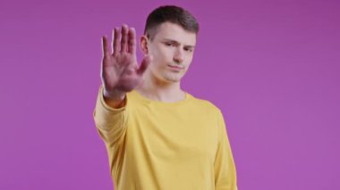 Avrupalı ciddi bir adam dur işareti ile reddedici bir hareket gösteriyor. Benimle oyun oynama. Adam pembe arka planda izole edilmiş. Yüksek kalite 4k