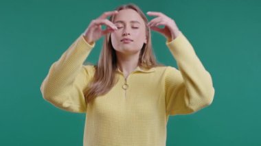 Sakin bir kadın dinleniyor, meditasyon yapıyor, stresi reddediyor. Sarışın kadın derin nefes alıyor, mavi stüdyo arka planını sakinleştiriyor. Yoga, ahlaki denge, zen konsepti. Yüksek kalite 4k