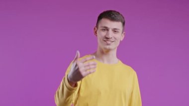 Yakışıklı genç adam arıyor. - Hey sen, buraya gel. Adam ona katılmayı teklif eder, el sıkışma hareketi ile çağırır. Oyuncu, çapkın, davetkar. Pembe stüdyo arka planı