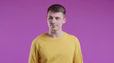Şşş, sır, sessizlik, komplo, dedikodu konsepti olan yakışıklı bir genç. Dudak dudağa gülümseyen adam, Violet stüdyo arka planı. Yüksek kalite 4k