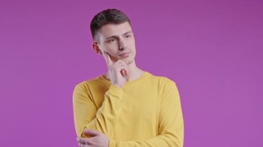 Zeki genç bir adam menekşe arkaplanını işaret ederek 