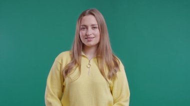 Dost canlısı genç kız evet işareti veriyor, başını sallıyor, onaylıyor. Olumlu gülümseyen Avrupalı kadın, vücut dili. Doğru mükemmel seçim, harika bir anlaşma. Yeşil stüdyo geçmişi. 4k