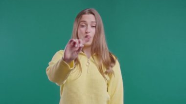 Parmak işaretini onaylamayan ilgisiz bir kadın. Benimle oynama, bu kadar yeter. Mavi arka planda genç bir bayanın portresi. Yüksek kalite 4k 