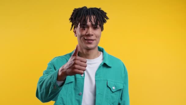 積極的なアフリカ系アメリカ人の男のような手のサインを 親指をジェスチャー 青で幸せな学生の男 正しい完璧な選択 大きな取引 黄色のスタジオの背景 高品質4K — ストック動画